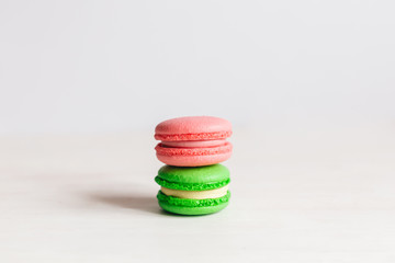 Tasty French macarons on a white wooden table. Pink and green macarons. White background.