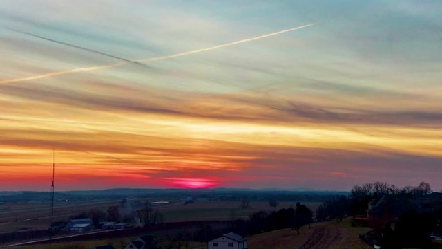 Aerial drone hyperlapse, timelapse of colorful sunset, jet chemtrail, contrail visible in sky