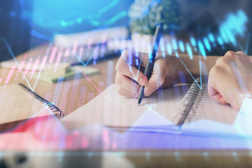 Financial forex graph drawn over hands taking notes background. Concept of research. Multi exposure