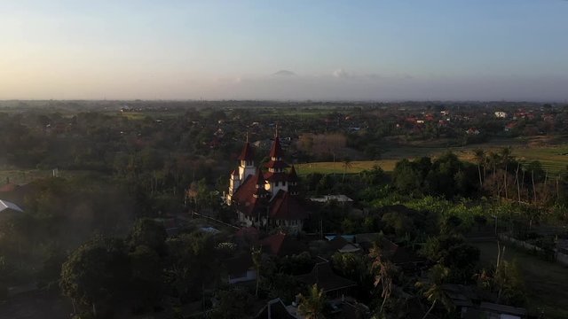Flying over the beautiful Kuta Utara in Indonesia with the Jemaat Marga Pakerti Church in the center during sunset - Aerial shot