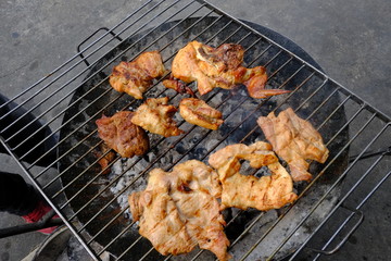 Grilled pork and Chicken wings on the roaster in street food stall, local Thai street food style. with selective focus