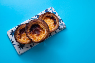 typical portuguese egg tart pastel de nata on blue paper background