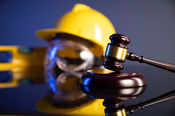 Construction law. Helmet and gavel on the blue background.