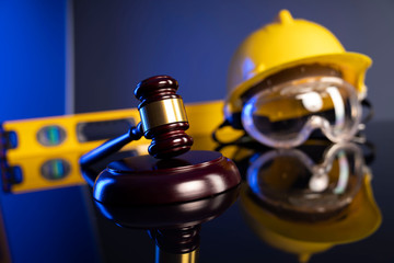 Construction law. Helmet and gavel on the blue background.