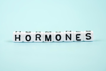 Hormones inscription on cubes. Medical blue background. Concept of estrogen, testosterone