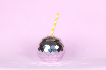 Creative disco cocktail shaped ball cup and paper straw with flash effect sparkle and shine on pink background. Concept for holidays and parties.