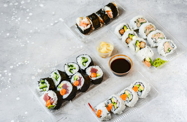 Food delivery concept. Lunch box with sushi set food delivery. Top view of assorted sushi, uramaki, hosomaki and nigiri. on grey office table. Lunch at the office. Top view , flat lay food, Takeaway,