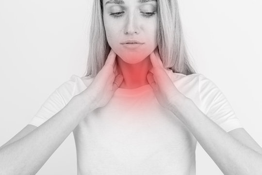 Female checking thyroid gland by herself. Close up of woman in white t- shirt touching neck with red spot. Thyroid disorder includes goiter, hyperthyroid, hypothyroid, tumor or cancer Health care.