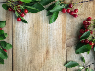 Fresh sweet cherries with leaves on wooden background, top view.