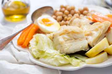boiled fish with vegetables and boiled egg on white plate