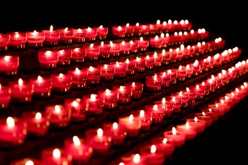 Group of red candles in church for faith resurrection prayer. Candlelight fire flames in rows are...