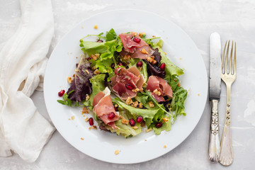 salad prosciutto with pomegranate on white plate