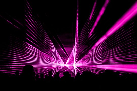 Pink laser show nightlife club stage with party people crowd. Luxury entertainment with audience silhouettes in nightclub event, festival or New Year's Eve. Beams and rays shining colorful lights