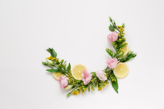Creative Arrangement Of Pink And Yellow Flowers With Lemons On A White Background With A Copy Space