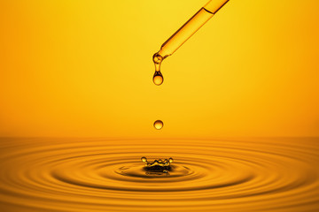 Golden Oil Drops on Yellow Background.