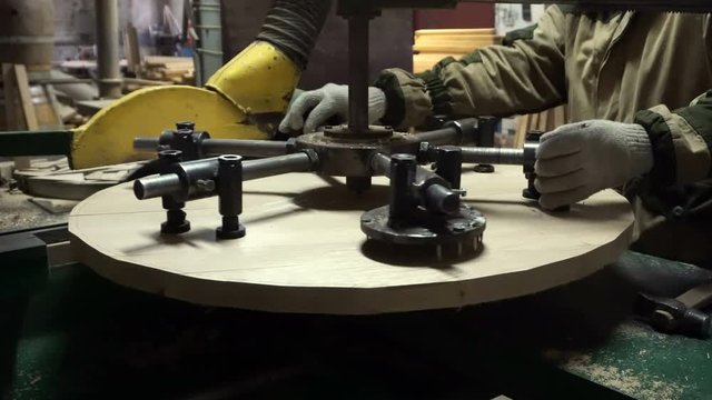 Making a wooden lid for a wine barrel on a modern woodworking machine in a cooper