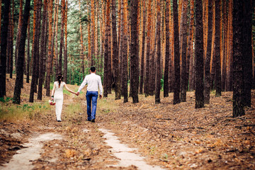 Fototapeta premium A guy with a girl walk through the forest along a country road in the mountains after rain