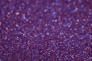 Abstract New Year purple bokeh background with shining defocus sparkles. Blurred glitters shimmering dust macro close up, copy space for text logo