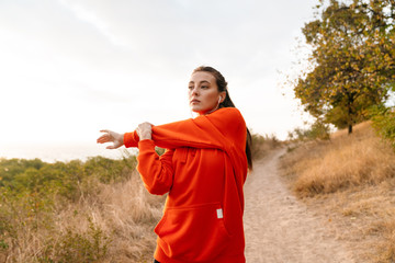 Photo of beautiful athletic woman using earphones and doing exercise