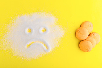 Fototapeta premium Salt scattered on black surface. Drawn sad face. Concept- diet, harm to health from excessive consumption of salt and sugar