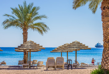 summer time vacation season palm beach straw umbrella south tropic scenic landscape waterfront shore line Red sea bay gulf of Aqaba view