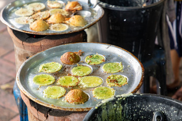 Making fresh coconut pancakes, They are made from coconut cream, rice flour and sugar, Pouring cream in the pan on stove, Sweet street snacks, Luang prabang, Laos.