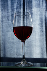 Vertical shot of glass of red sweet wine against blue background