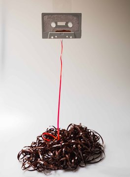 Leeds, UK, 03/02/19Cassette unspooled with loose tape tangled up around itself shot on isolated on a white background professionally with studio lighting and old retro vintage media unused now