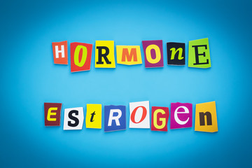 Text - hormone estrogen. Cut colorful letters on blue background. Writing on banner, card. Inscription, message on poster from colored letters.