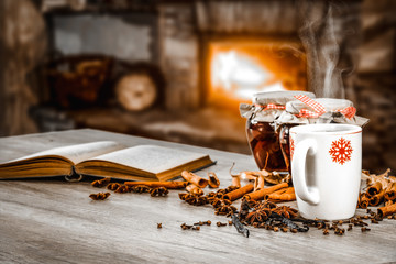 Naklejka na ściany i meble Mug of hot mulled on table.Free space for your decoration.Blurred background of fireplace in home.Cold december night. 