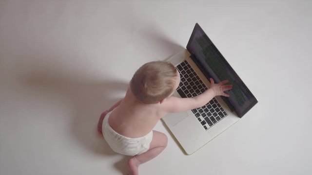 Adorable baby looking at laptop, education concept. Top view