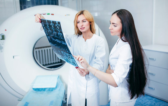 Two beautiful model girls doctors examine CT Scan picture