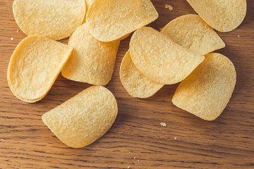 Delicious potato chips, laying on wooden table background
