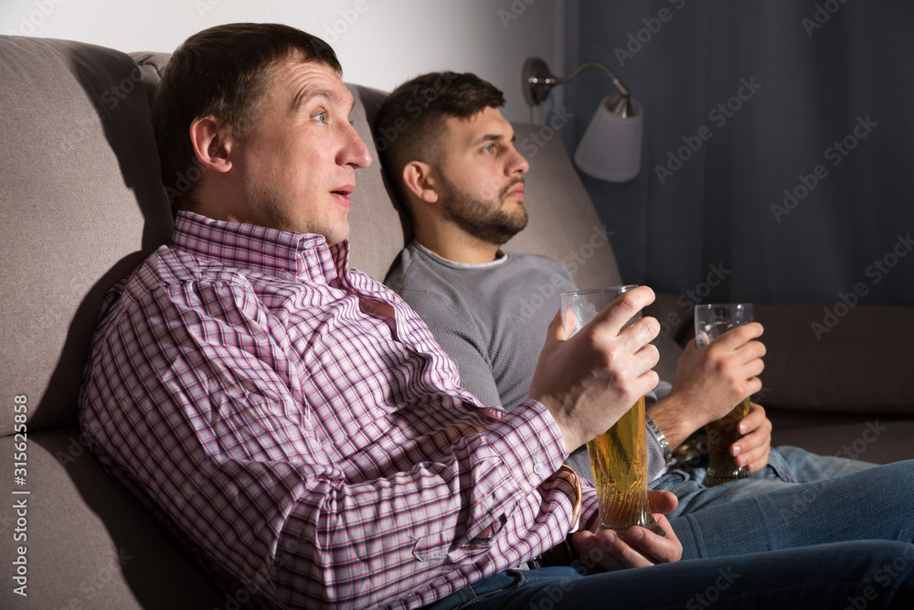 Wall mural two men watching tv on sofa with beer