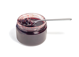 Side view of conserve or jam with red berries in transparent glass jar and silver spoon. Tasty food ingredient isolated on white background.