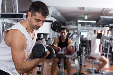 Fototapeta na wymiar Man doing exercises with dumbbells at gym