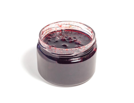 Side view of conserve or jam with red berries in transparent glass jar. Tasty food isolated on white background.