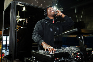 African american dj play music on decks at night club.