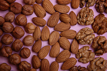 Peeled hazelnut, almonds, walnuts on a pink background. Nutritional table.