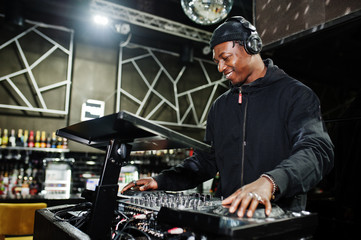 African american dj play music on decks at night club. - Powered by Adobe