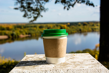 Coffee cup on the concrete standing. Beautiful autumn nature.