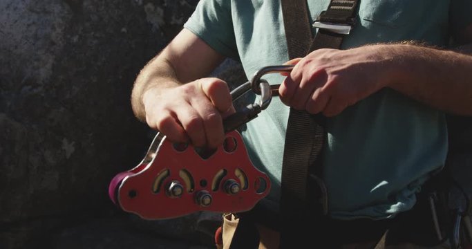 Young Caucasian man fastening zip lining harness