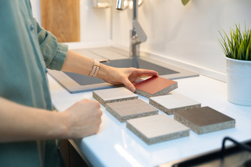 woman choosing kitchen countertop material texture from samples