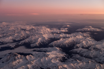 Snow covered Pyrénées mountains in the south of France from the airplane window at sunset