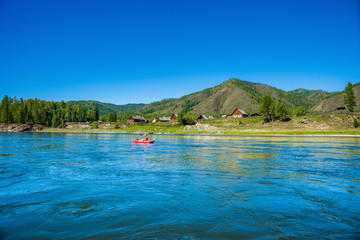 Kayaker against old believers village on the siberian river Small Yenisei bank.
