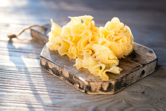Sliced Swiss Tete de moine cheese and served on a wooden board.