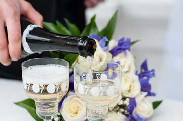Glasses of champagne and bridal bouquet. Groom pouring champagne glasses wedding. Can be used for greeting cards, wedding invitations and advertising services.