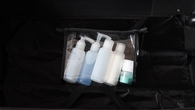packing for a holiday concept, luggage with transparent liquid bag for airport security screening compliance camera panning vertically