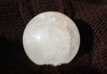 cCystal quartz ball on brown textured background, macro photography, closeup