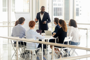 African American male coach make flip chart presentation for employees